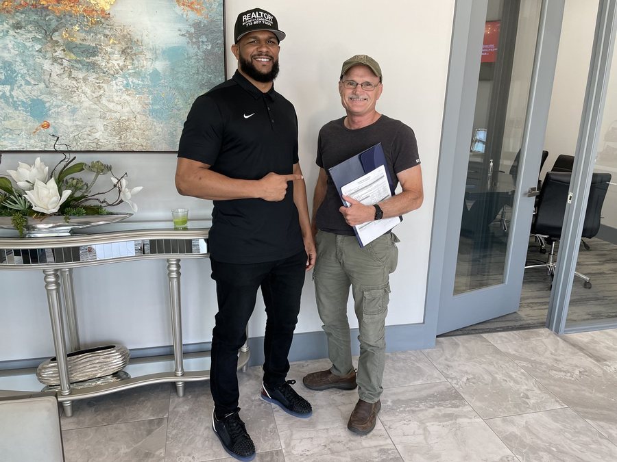 Mr. Wright smiling beside a client holding signed documents
